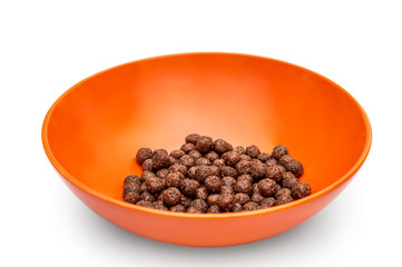 Chocolate cereal balls on the bottom of orange bowl. Isolated on white