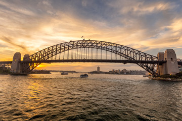 View of Sydney harbor bridge at sunset and a boat sailing in the background