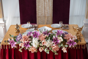 Festive table in red and gold colors decorated with flowers