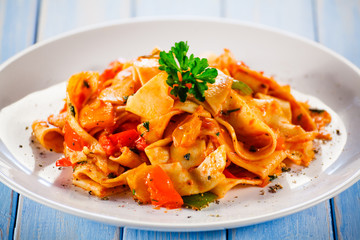 Pasta with meat, tomato sauce and vegetables on wooden table