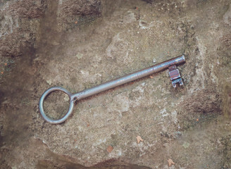 small metal retro key that lies on a rocky background