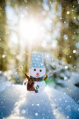 Happy snowman standing in winter christmas landscape. Snowman smiling standing in snow near spruce trees