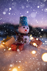 Happy snowman with gift boxes standing in winter christmas landscape. Snowman in mountains