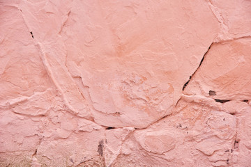 Fototapeta premium Textured background pink cracked plaster partially sprinkled with a dark rose shaded cracked wall. Grunge background