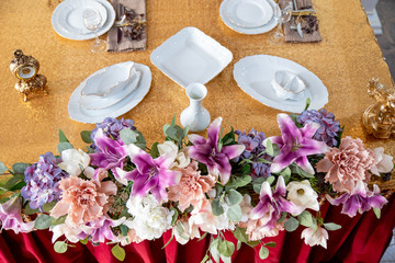 Table setting with Cutlery and white plates with brown napkin on Golden tablecloth