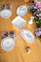 Served table with white plates on a Golden tablecloth