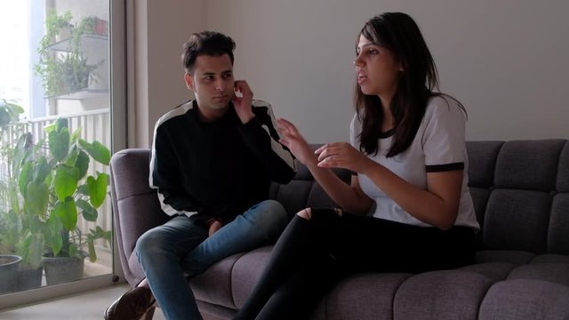 Young husband apologies for his mistakes and asks for forgiveness holding one ear but she is still pissed and sulking 