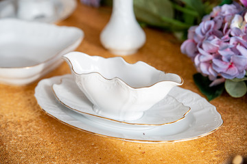 Served table with white plates on a Golden tablecloth