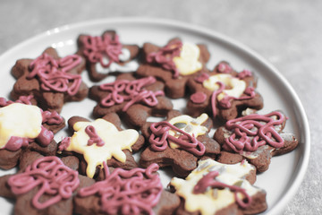 Closeup of traditional homemade decorated colorful gingerbread cookies for christmas on white plate at shallow depth of field.