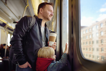Mature man and his little son looks out the window of the car in the subway in new York.