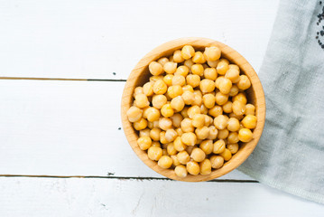 cooked chick pea and sesame seeds, hummus ingredients on cotton canvas, white wooden table background
