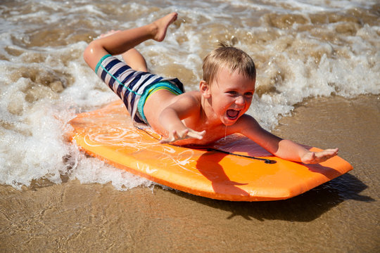 Young boy body boarding fearlessly in shallow waves.