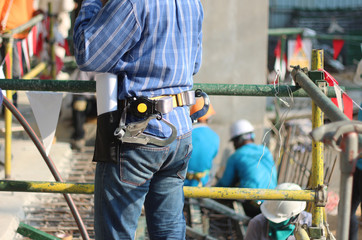 worker installing steel column on scaffolding in construction site