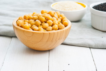 cooked chick pea and sesame seeds, hummus ingredients on cotton canvas, white wooden table background