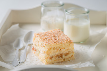 Tasty coconut cake with nuts and foam on white table