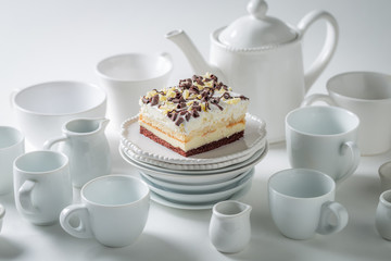White cake with mousse, chocolate and porcelain on white background