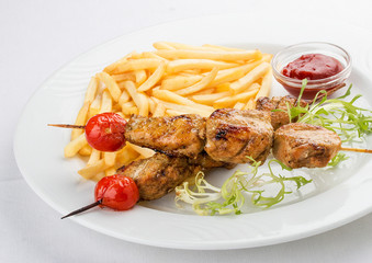 French fries with chicken skewer with red sauce. On white background