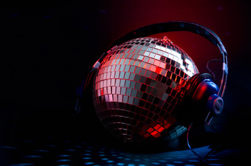 Nightclub music and nightlife concept with a disco ball cover in mirror wearing headphones...