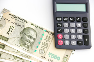 Close up view of calculator and brand new indian 500 rupees banknotes on white background.