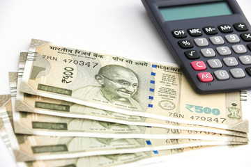 Close up view of calculator and brand new indian 500 rupees banknotes on white background.