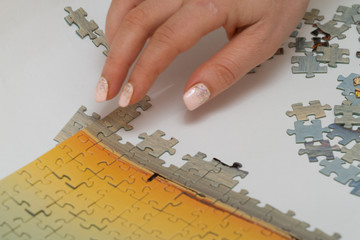 Hands of two women which assemble world map puzzle on table