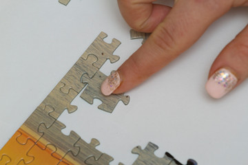 Hands of two women which assemble world map puzzle on table