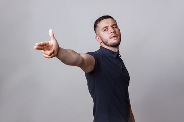 Portrait of a young man shooting gesture. Handsome straightened his hand forward and takes aim for...
