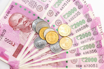 Close up view of brand new indian 2000 rupees banknotes and coins on white background.