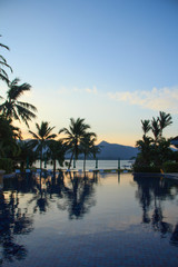 Fototapeta na wymiar Beautiful sunrise over the pool and palm trees