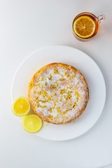 Homemade lemon pie with a cup of tea on a white wooden table