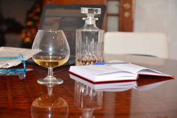 bicchiere e bottiglia di liquore cognac con notebook giornale occhiali lavoro e hobbies
