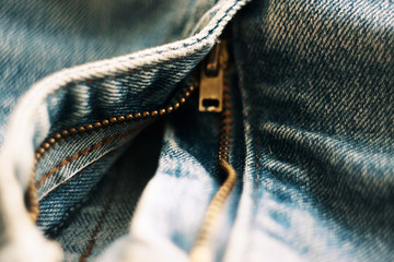 open the brass zipper on blue jeans made of coarse cloth
