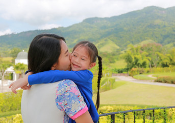 Asian mother carrying daughter on balcony at hillside