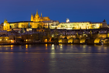 Night colorful snowy Christmas Prague Lesser Town with gothic Castle and Charles Bridge, Czech republic