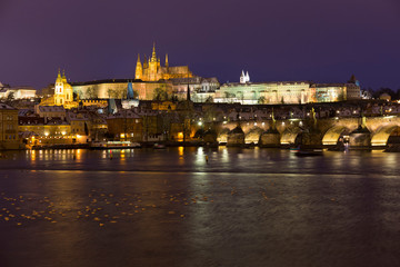 Night colorful snowy Christmas Prague Lesser Town with gothic Castle and Charles Bridge, Czech republic