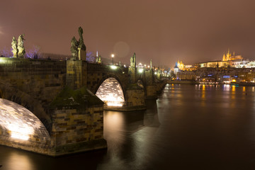 Fototapeta premium Night colorful snowy Christmas Prague Lesser Town with gothic Castle and Charles Bridge, Czech republic