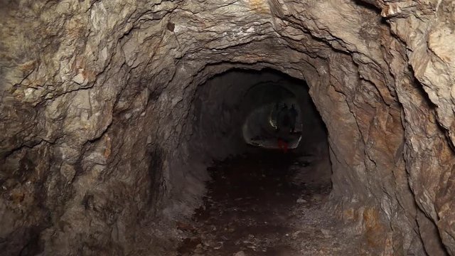 A man with a flashlight goes through an abandoned uranium mine