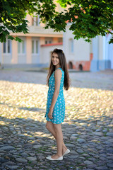 Young smiling girl in summer dress on sunset background of city