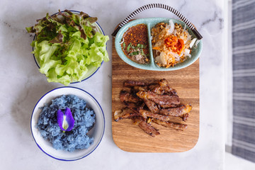 Roasted pork and Butterfly Pea purple sticky rice served with spicy Thai style sauce and Green Oak Lettuce.