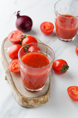 Glass of healthy tomato juice with minearl substances.Fresh tomatoes on white table, vertical photo