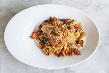 Top view of Dried Spaghetti Chili Bacon served in white bowl plate on marble table.