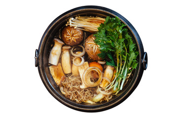 Isolated top view of Sukiyaki hot pot with boiling vegetables including cabbage, konjac noodle, onion, carrot, shiitake, enokitake and tofu in Shoyu sauce soup.