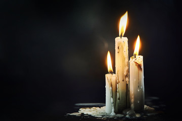 Group of white candles burning in the dark