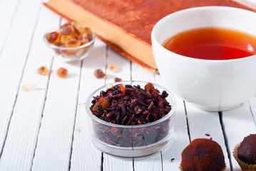 herbal tea, brown sugar, chocolate truffles and an old book on white wooden table