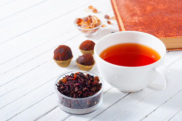 herbal tea, brown sugar, chocolate truffles and an old book on white wooden table