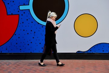 A young lady using mobile phone against a colourful background