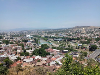 Fototapeta premium View of Tbilisi from Mtsatminda mountain. Old Town, new houses, the Kura River.