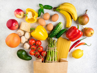 Healthy food background. Healthy food in paper bag vegetables, fruits, pasta, eggs, cheese, banana and mushrooms on white. Shopping food supermarket concept