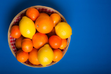 basket of various citruses fruit  - oranges, lemons and mandarins over blue background 