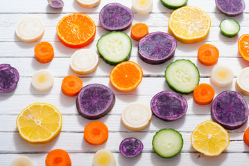 sliced fruits and vegetables on white wood table background